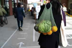 Photo gratuite vue arrière femme portant un sac avec des fruits