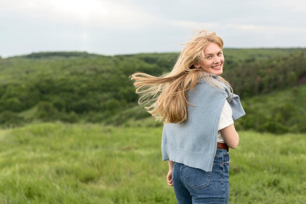 Vue arrière de la femme posant à l'extérieur dans la nature