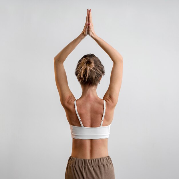 Vue arrière de la femme pratiquant le yoga à la maison