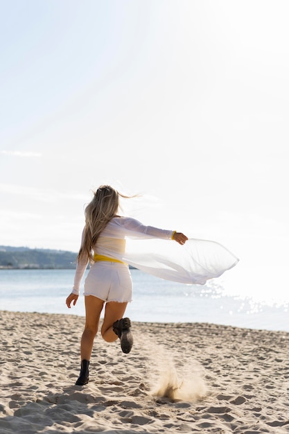 Vue arrière de la femme qui court sur le sable de la plage