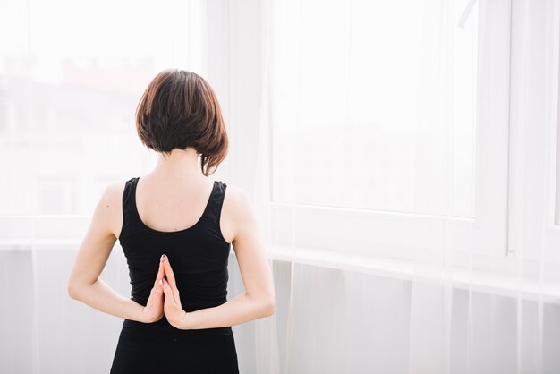 Vue arrière de la femme qui s'étend sa main pendant le yoga