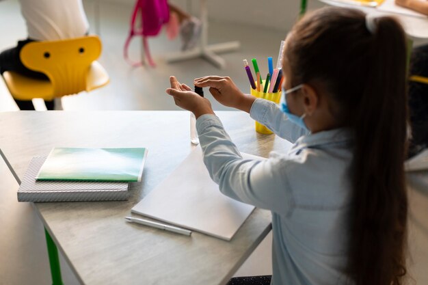 Vue arrière fille désinfectant ses mains