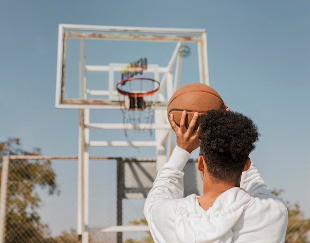 Vue arrière de l'homme afro-américain jouant avec un ballon de basket à l'extérieur