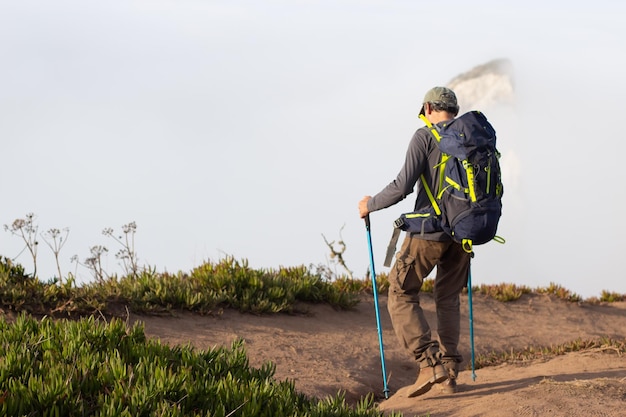 Vue arrière d'un homme âgé en randonnée le jour de l'été. Sportif avec sac à dos en montée. Loisirs, concept sportif