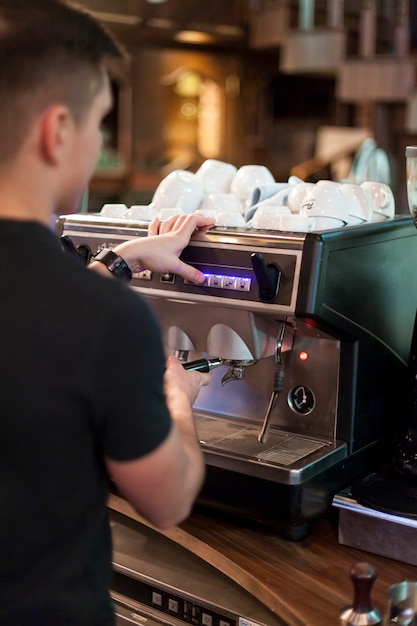 Photo gratuite vue arrière homme à l'aide de la machine à café