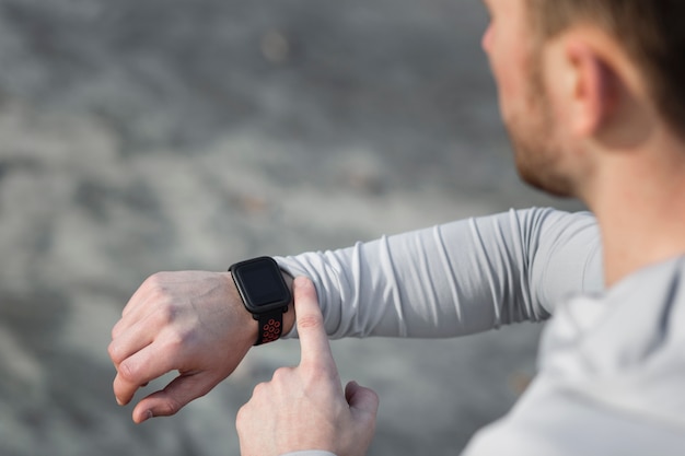 Vue arrière homme ajustant sa montre de sport