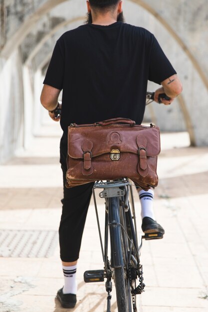 Vue arrière d&#39;un homme assis sur un vélo avec un sac marron