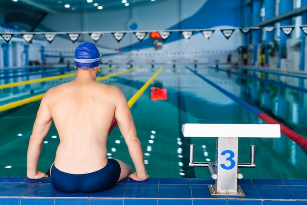 Vue arrière homme debout sur le bord de la piscine