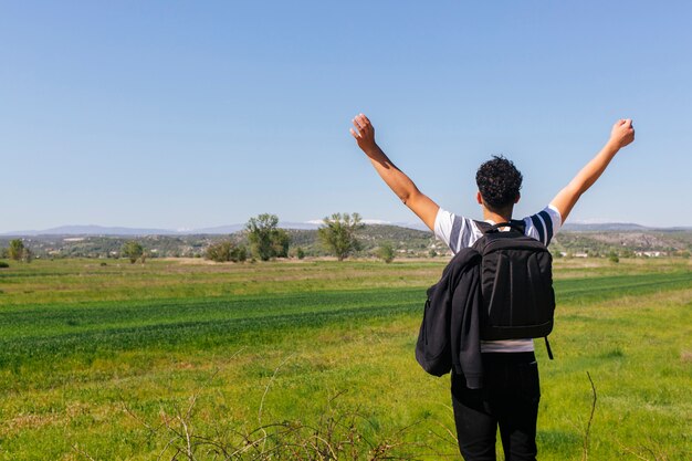 Vue arrière de l&#39;homme debout près de beau paysage vert avec sac à dos