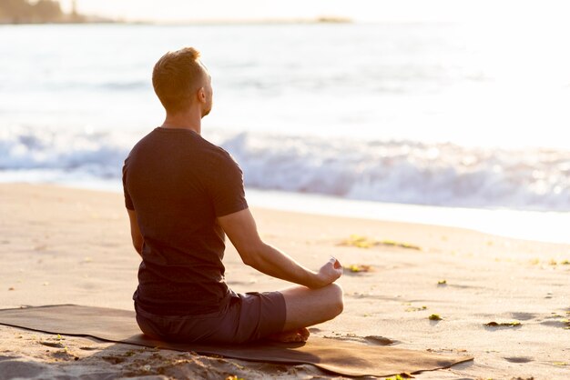 Vue arrière de l'homme de détente sur la plage à l'extérieur