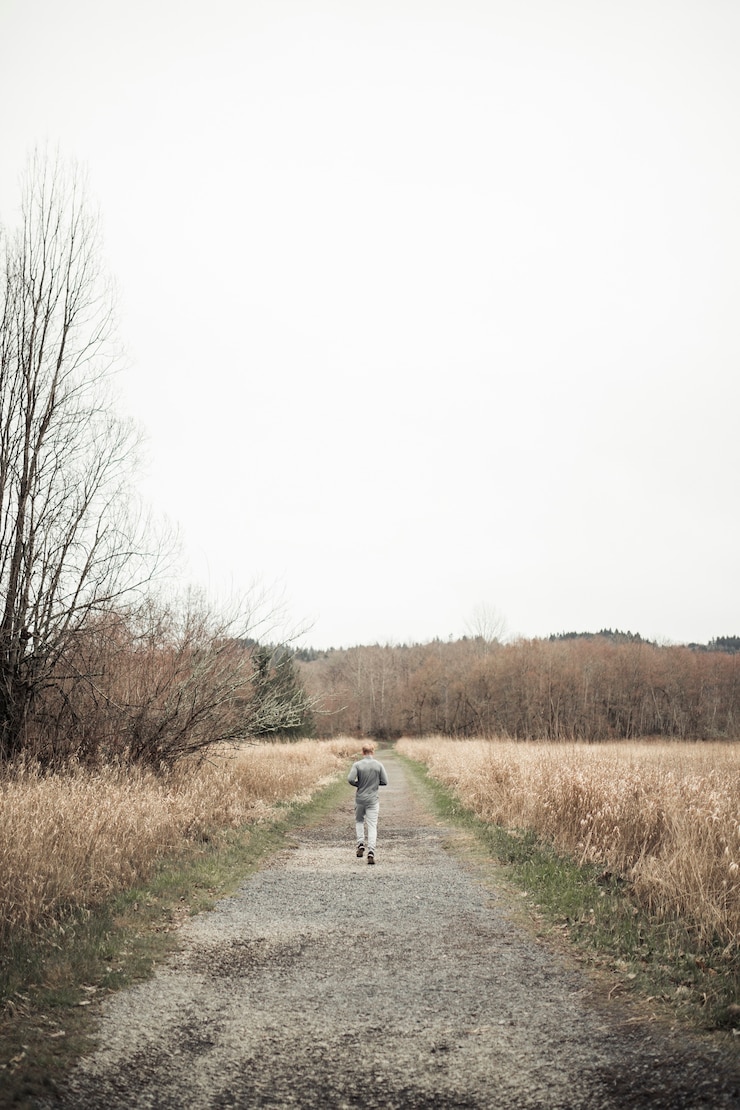 Photo gratuit vue arrière de l&#39;homme, faire du jogging sur le chemin de terre au milieu du champ