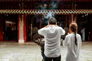 Photo gratuite vue arrière de l'homme et de la femme priant au temple avec de l'encens brûlant