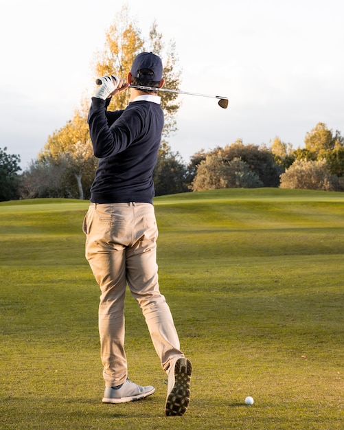 Vue arrière de l'homme jouant sur le terrain de golf herbeux