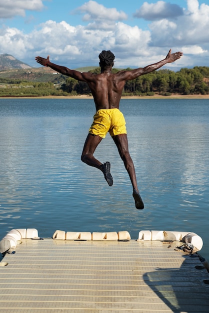 Vue arrière homme sautant dans le lac