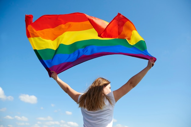 Vue Arrière De La Jeune Femme Agitant Le Drapeau Arc-en-ciel