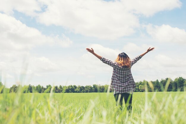 Vue arrière de la jeune femme à bras ouverts dans la prairie