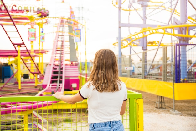 Vue arrière d&#39;une jeune femme debout au parc d&#39;attractions