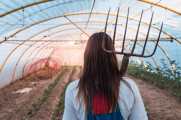 Vue arrière d'une jeune femme avec un outil de râtelage d'herbe