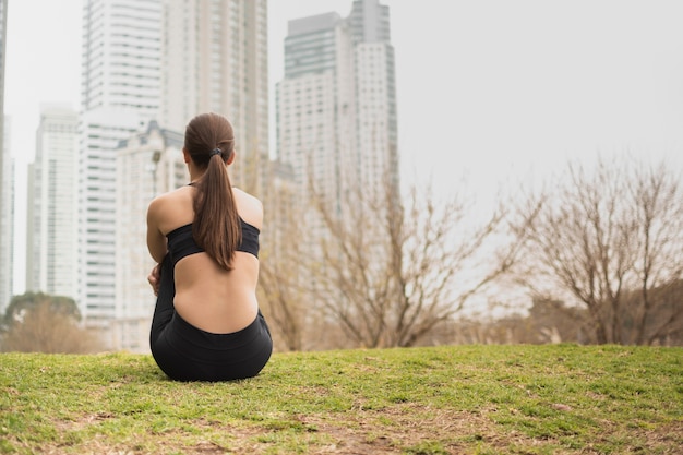 Vue arrière jeune fille assise sur l'herbe