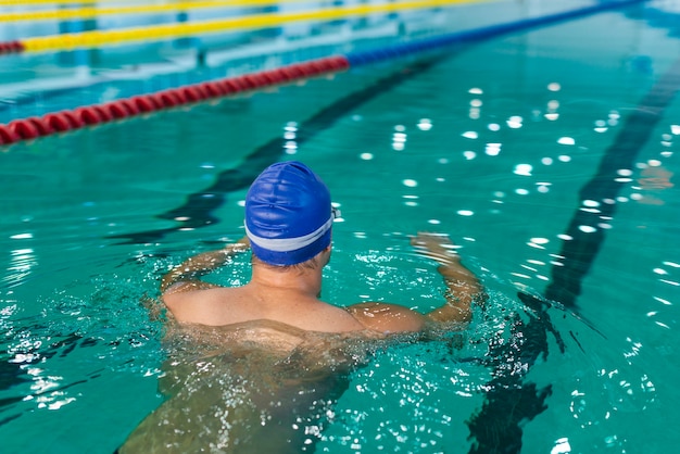 Vue arrière mâle nageant dans la piscine