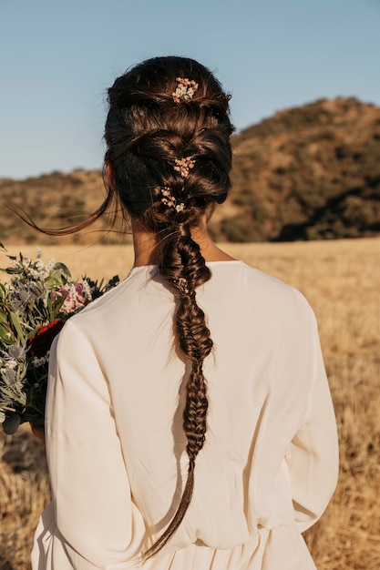 Photo gratuite vue arrière de la mariée tenant un bouquet de fleurs