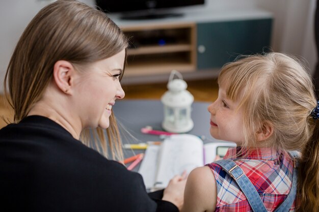 Vue arrière mère et fille à faire leurs devoirs