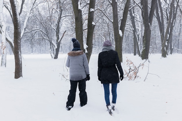 Vue arrière de la mère avec sa fille marchant dans la forêt au jour de l&#39;hiver