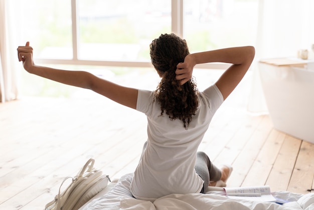 Vue arrière petite fille qui s'étend après un bon sommeil