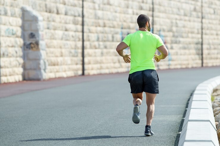 Photo gratuit vue arrière de strong sporty man running on road