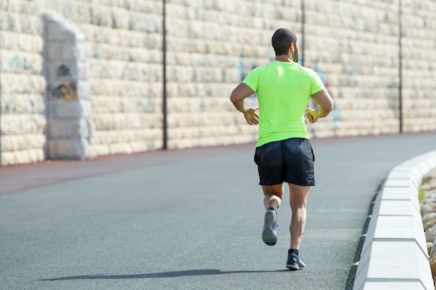 Vue arrière de Strong Sporty Man Running on Road