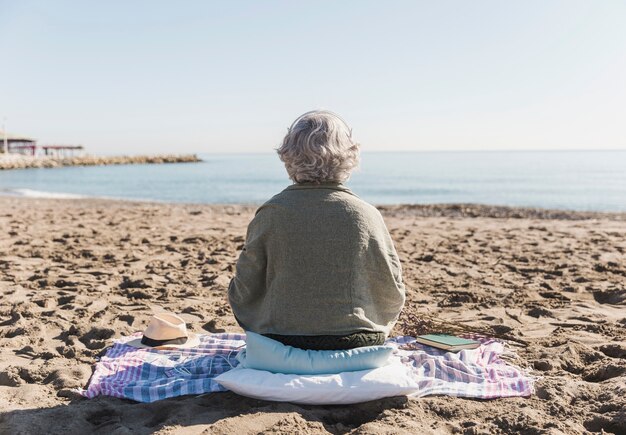 Vue arrière vieille femme sur la plage