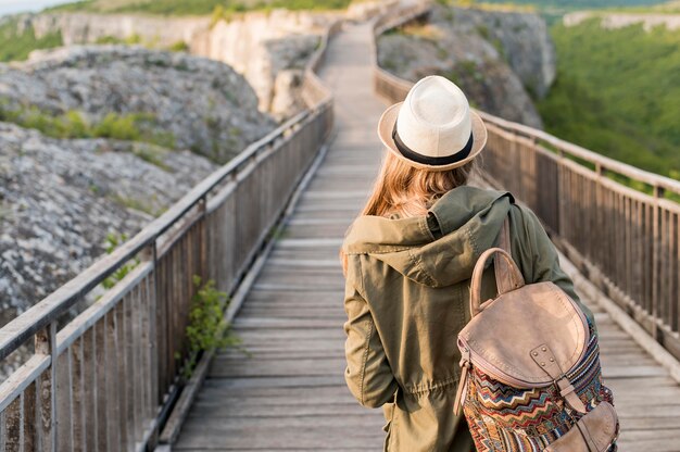 Vue arrière voyageur élégant avec chapeau marchant