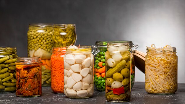 Vue avant de l'assortiment de légumes marinés dans des bocaux en verre transparent