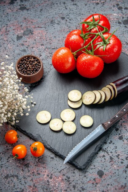 Vue avant d'aubergines noires avec des tomates rouges fraîches fond bleu