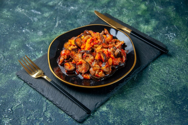 Vue avant d'aubergines en sauce cuite à l'intérieur de la plaque noire sur fond sombre