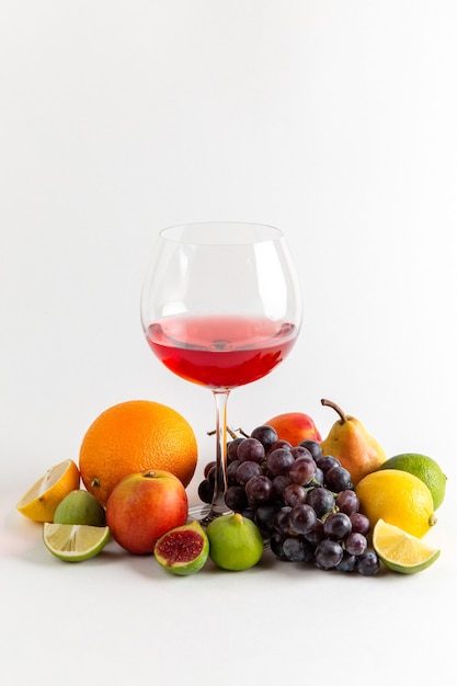 Vue avant de boire de l'alcool rouge à l'intérieur du verre avec différents fruits frais sur un mur blanc boisson alcoolisée bar à whisky