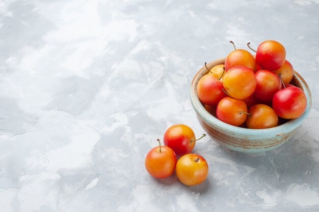 Photo gratuite vue avant de la cerise-prunes fraîches aigre et frais à l'intérieur du pot sur le bureau léger fruits aigre frais moelleux