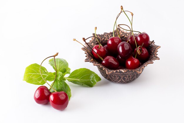 Vue avant de cerises aigres rouges à l'intérieur de la plaque brune sur blanc