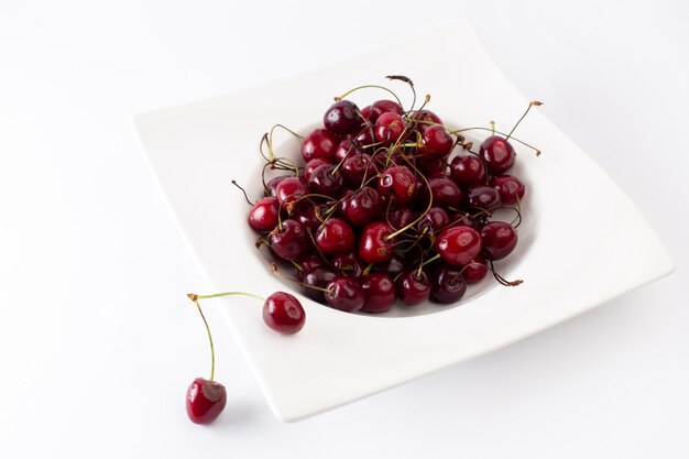 Vue avant de cerises moelleuses aigres à l'intérieur de la plaque blanche sur blanc