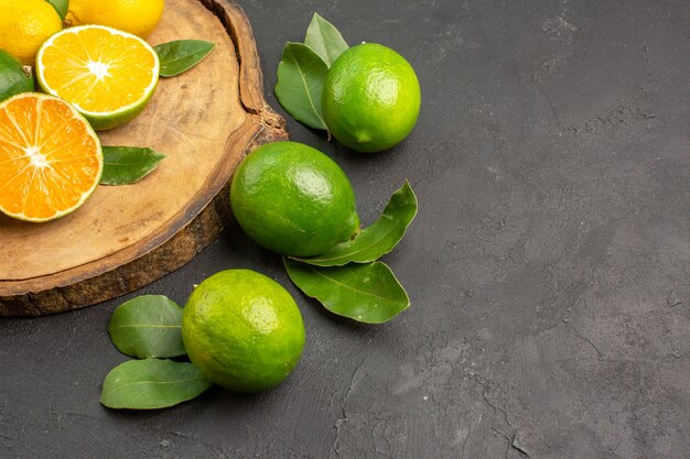 Vue avant des citrons frais sur le bureau sombre fruits lime agrumes aigre