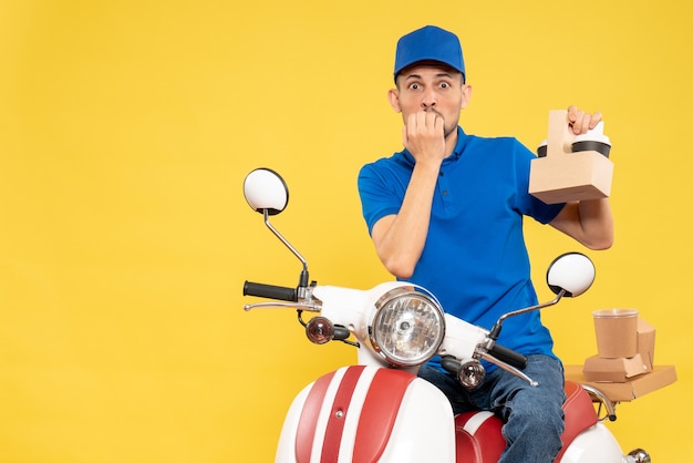 Vue avant de courrier masculin en uniforme bleu avec du café peur sur la livraison de travail jaune couleur travail travailleur service uniforme de vélo