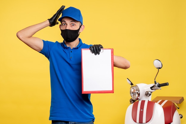 Photo gratuite vue avant de courrier masculin en uniforme bleu tenant note de fichier sur le service d'emploi jaune covid- livraison travail uniforme de couleur pandémique