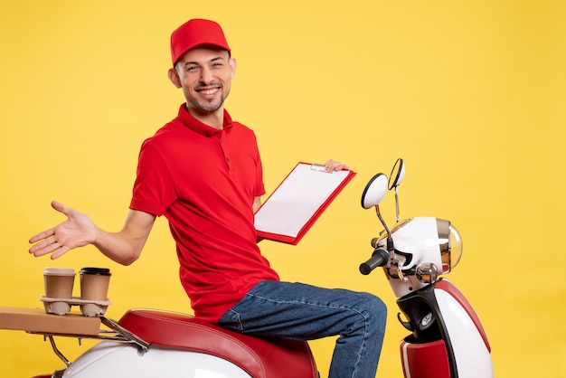 Vue avant de courrier masculin en uniforme rouge avec note de fichier sur la livraison de couleur jaune vélo travail uniforme de travail de service des travailleurs