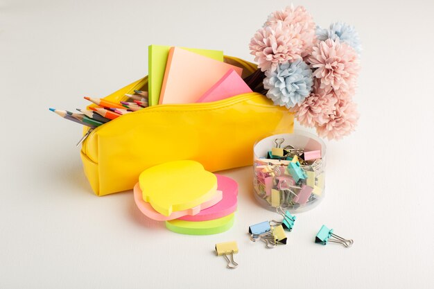 Photo gratuite vue avant des crayons colorés avec boîte à stylos et autocollants sur un bureau blanc