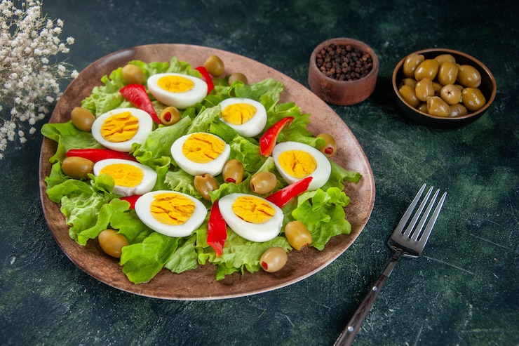 Photo gratuit vue avant de la délicieuse salade aux œufs se compose d'olives et de salade verte sur fond sombre
