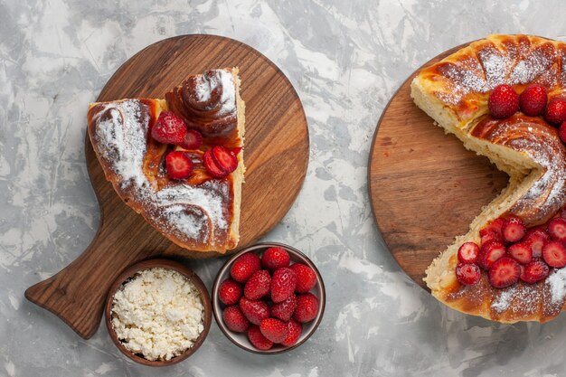 Vue avant de la délicieuse tarte aux fraises cuit au four et une délicieuse tranche de dessert sur une surface blanche