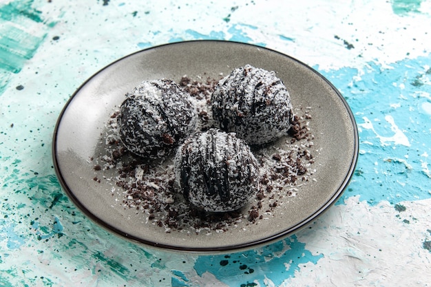 Vue avant de délicieuses boules de chocolat gâteaux au chocolat rond formés avec du glaçage sur la surface bleue gâteau biscuit chocolat au sucre