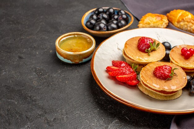 Vue avant de délicieuses crêpes aux fruits et olives sur une surface sombre gâteau aux fruits sucrés