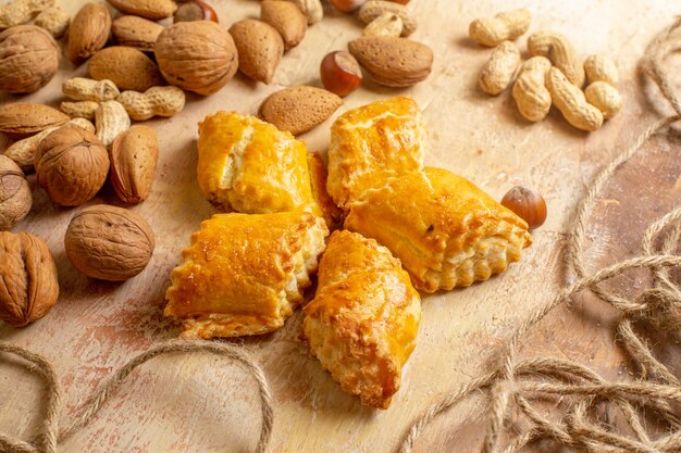 Vue avant de délicieuses pâtisseries aux noix avec des écrous sur le bureau brun gâteau sucré tarte aux noix