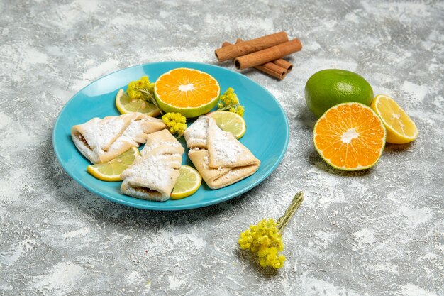 Vue avant de délicieuses pâtisseries de pâte avec des tranches de citron sur un mur blanc léger pâtisserie au sucre cuire la pâte à gâteau sweet pie cookie